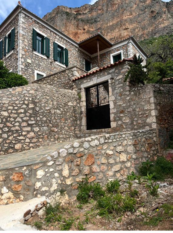 a stone building with a door on a stone wall at Sunshine 1 in Leonidio