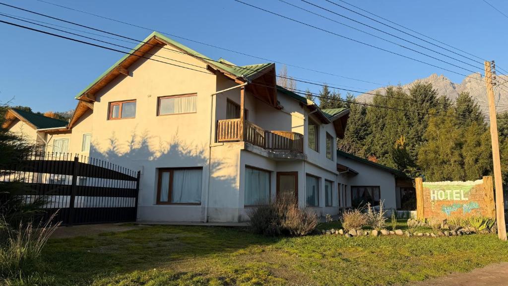 a white house with a porch and a balcony at Hotel Hielo Azul 1 in El Bolsón