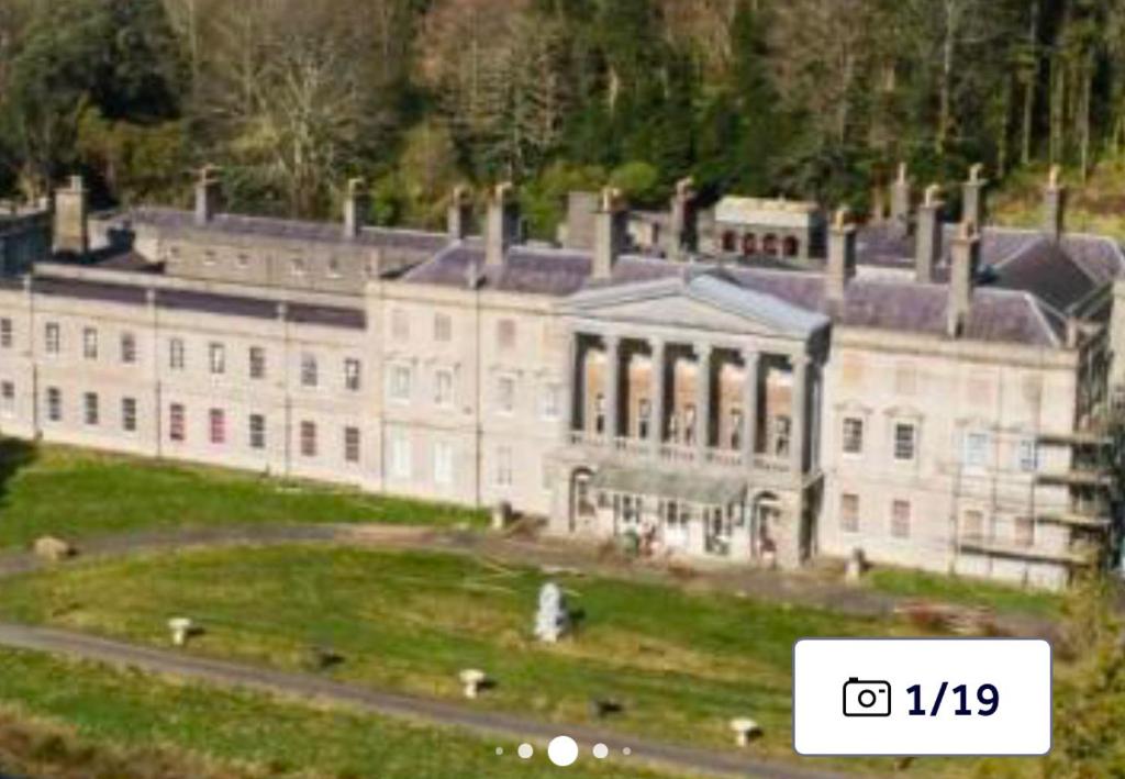 a large white building with four chimneys on it at Plas Glynllifon Mansion in Caernarfon