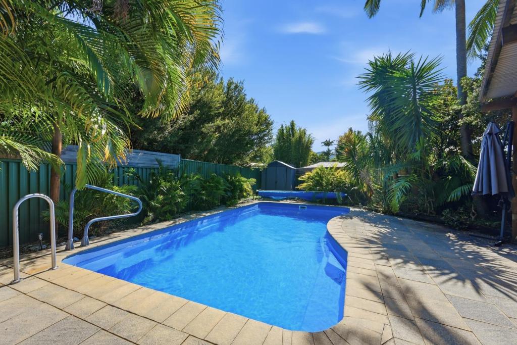 a swimming pool in a yard with palm trees at 2 Long between breaks in Coffs Harbour