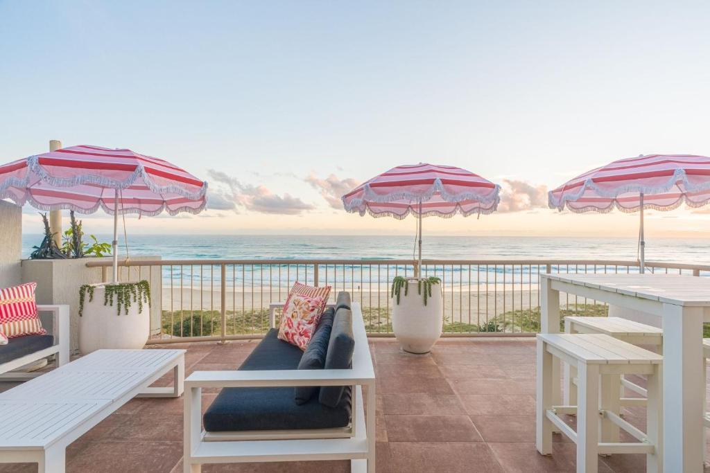 a patio with tables and umbrellas and the ocean at Seacrest 9 in Gold Coast