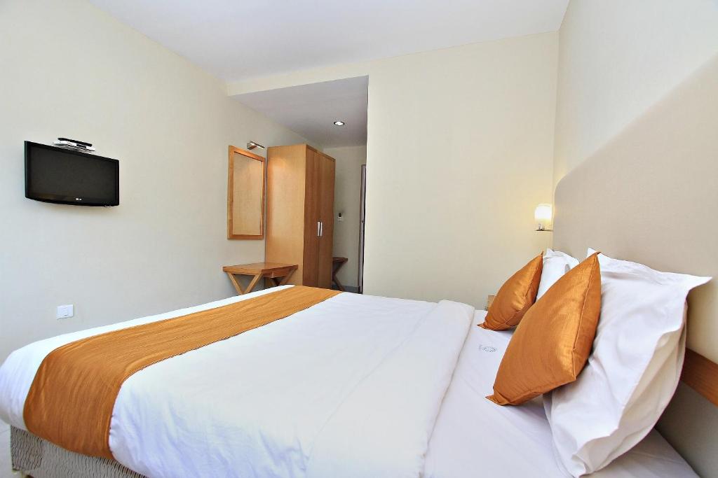 a hotel room with a large bed with orange pillows at Super Townhouse Hills Palace in Ooty
