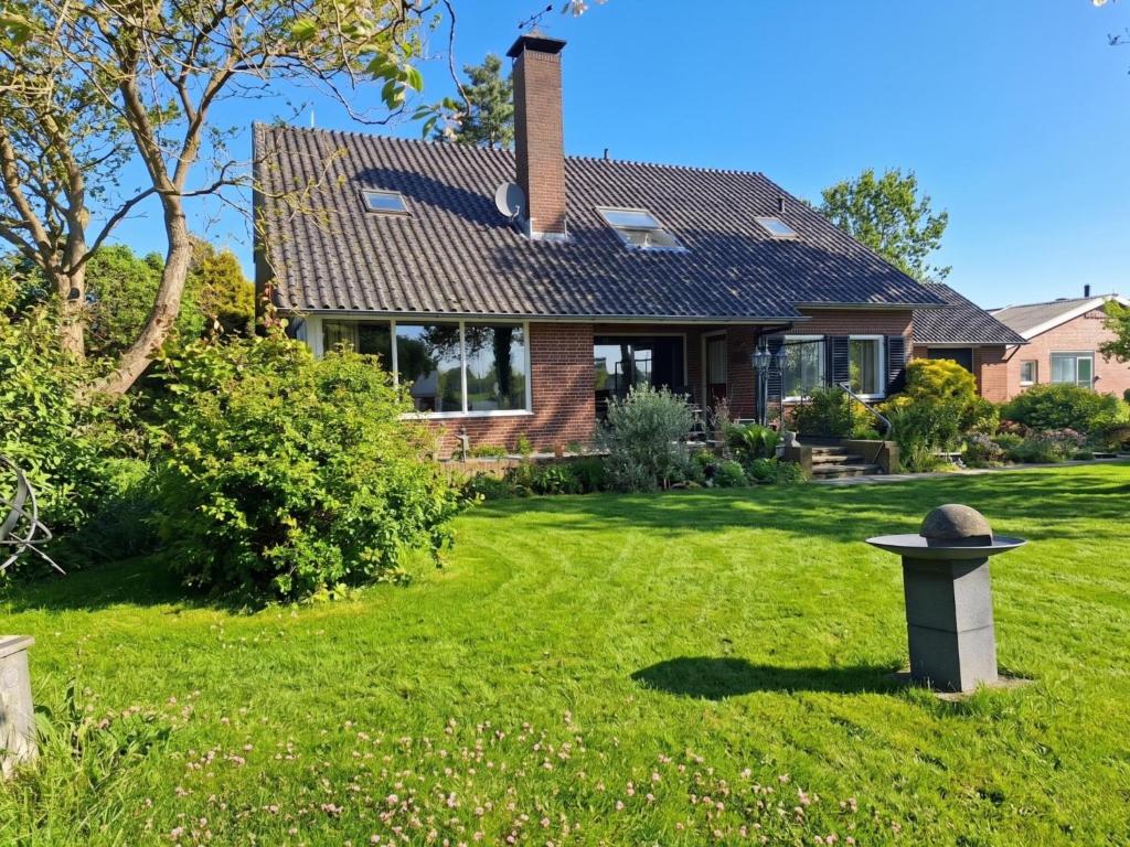 a house with a green yard with a birdbath at Genderens Buiten in Genderen