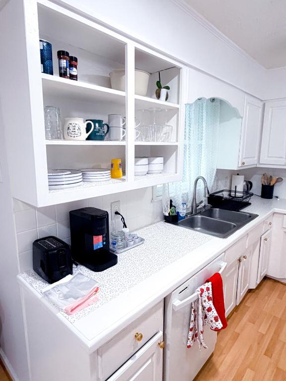 a white kitchen with a sink and white cabinets at Comfort Cove Snellville in Snellville