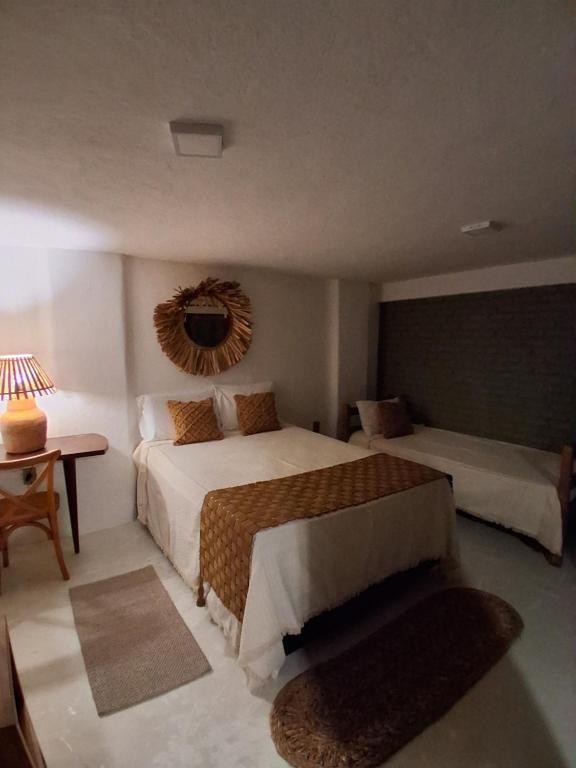 a bedroom with two beds and a table with a lamp at Casa Irmã Lua in Porto Seguro