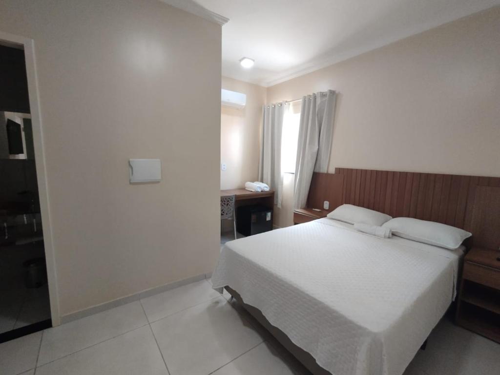 a bedroom with a white bed and a window at Pousada Posto Junior - Madalena CE in Madalena