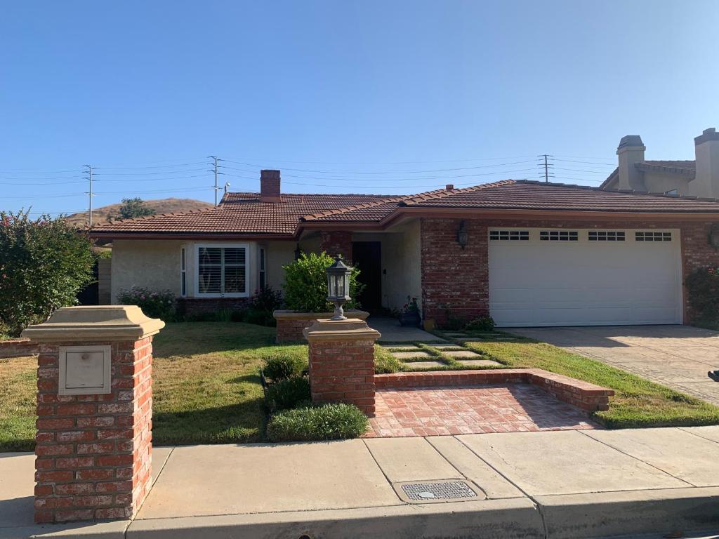 a brick house with a white garage door at Spacious 3 bedrooms 1 bath Jacuzzi BBQ SINGLE HOUSE in Agoura Hills