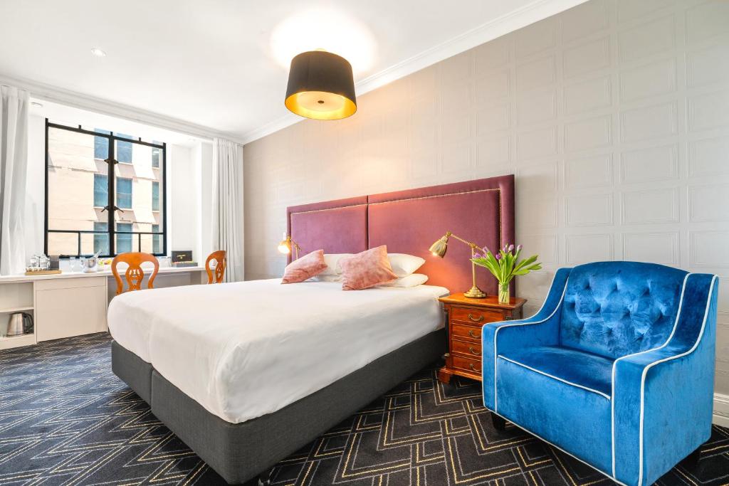 a bedroom with a bed and a blue chair at Castlereagh Boutique Hotel, an Ascend Collection Hotel in Sydney
