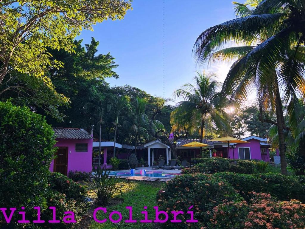 a resort with a pool and palm trees at Rancho Colibrí in Acajutla