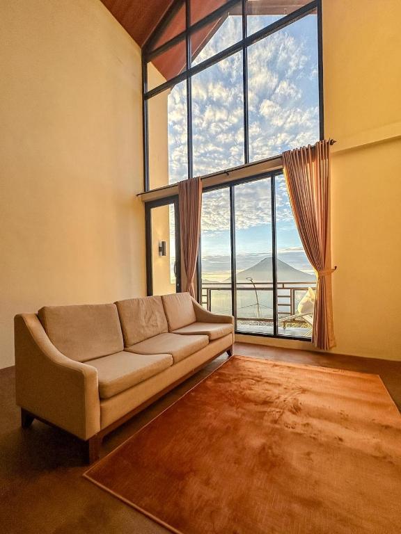 a living room with a couch and a large window at Zambrud Villa Dieng in Kejajar