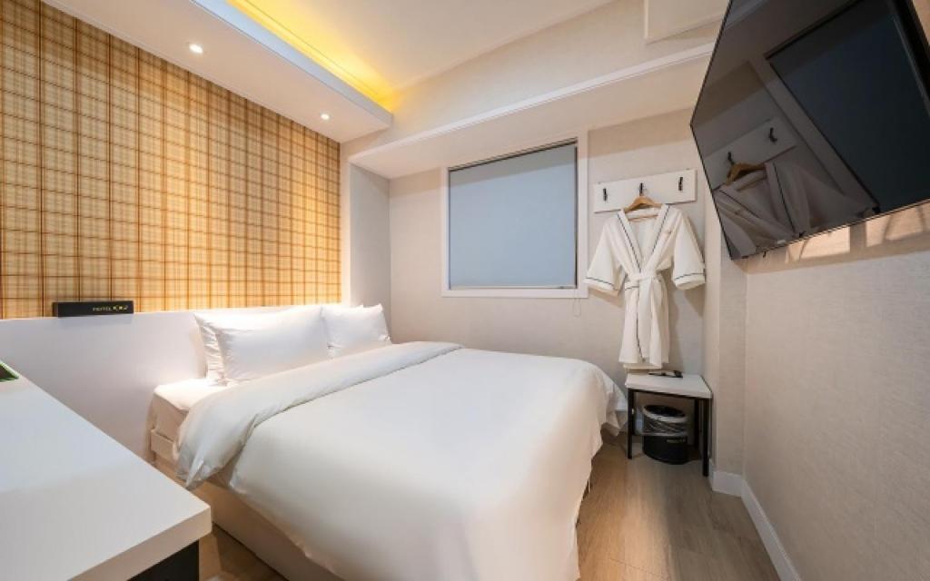 a bedroom with a large white bed and a window at Osan No25 Hotel in Osan