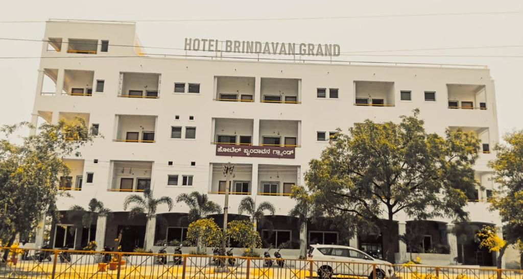 a white building with a car parked in front of it at Hotel Brindavan Grand in Gulbarga