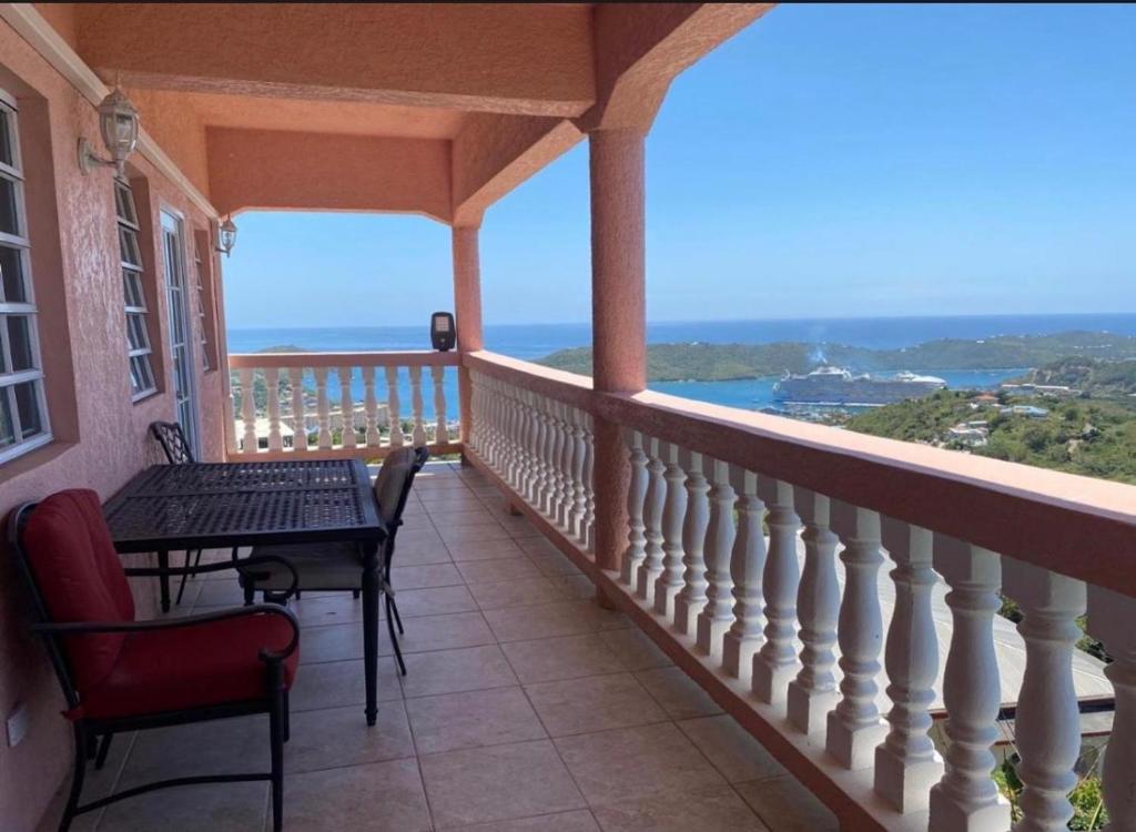 a balcony with a table and chairs and a view of the ocean at Cozy House, Ocean View, Saint Thomas in Contant