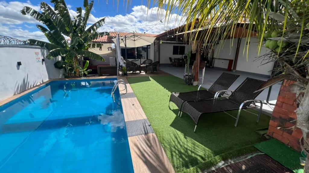 a backyard with a swimming pool and chairs and a house at Recanto Guarujá Moc in Montes Claros