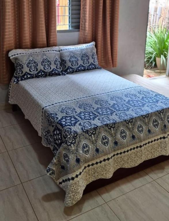 a bed with a blue and white blanket and pillows at Chalés Mirante da Lua Chalé 4 in Cavalcante