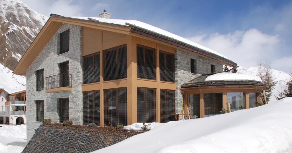 ein Haus im Schnee vor einem Berg in der Unterkunft Grischuna Mountain Lodge in Samnaun