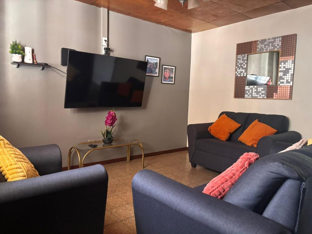 a living room with two couches and a flat screen tv at Casa de Helen in Antiguo Cuscatlán