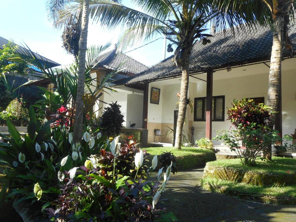 a house with palm trees and plants in front of it at Manik Villa Besakih in Besakih