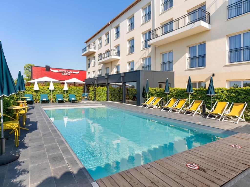a swimming pool in front of a hotel at Ibis Styles Miramas in Miramas