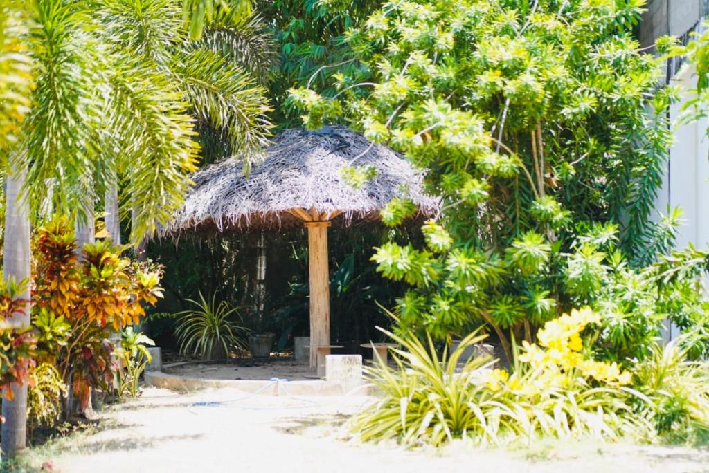 a straw umbrella in a garden with palm trees at Grace Inn in Kalkudah