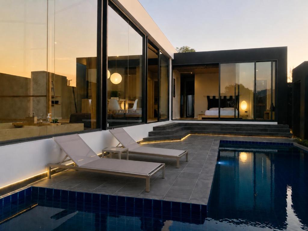 a swimming pool with two lounge chairs next to a house at Villa Kyoto in Layan Beach