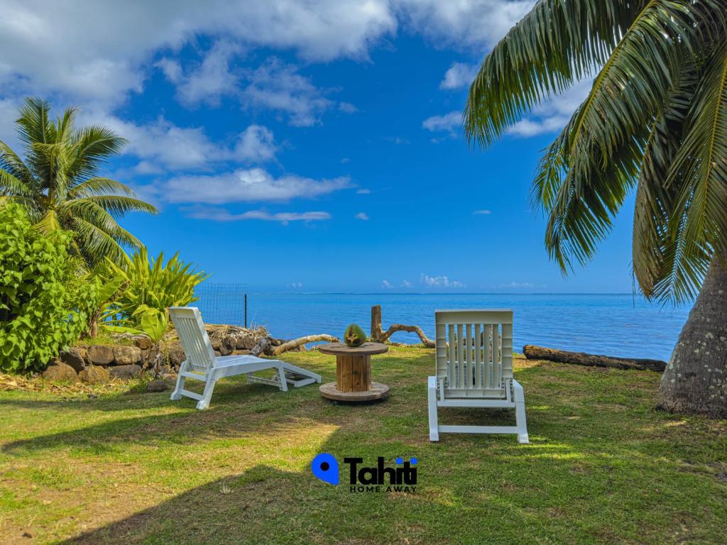 two chairs and a table with the ocean in the background at Tekehani Lodge in Araito