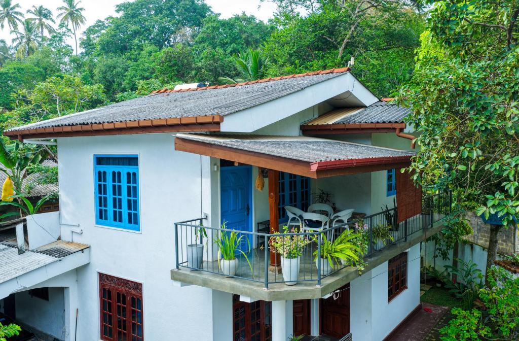a house with a blue door and a balcony at Blissful House Two Bedroom Apartment Thalpe Beach in Galle