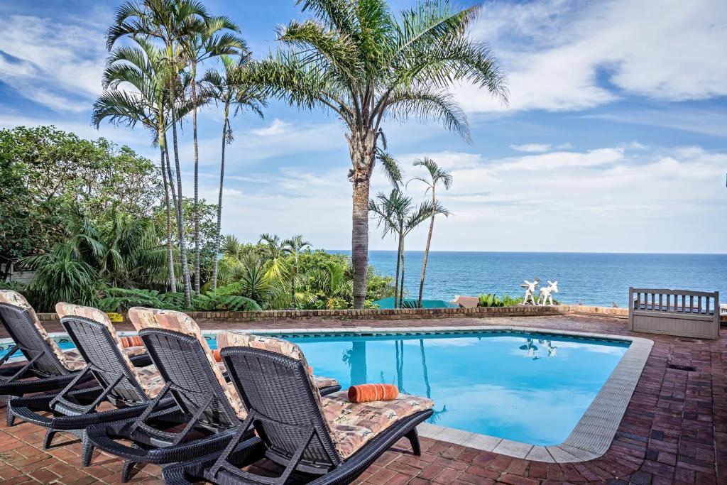 una piscina con sedie e l'oceano sullo sfondo di Albatros Guest House, Margate ,, SOUTH AFRICA , KZN NATAL a Margate