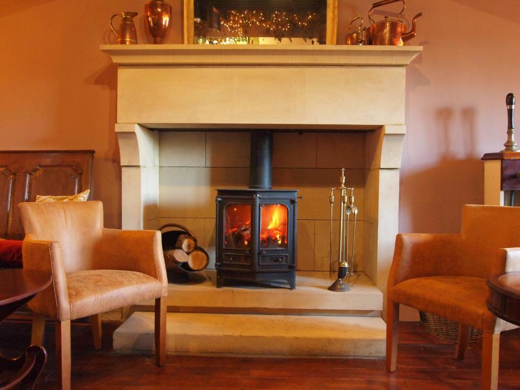 a fireplace with a stove in a room with chairs at Black Swan Inn in Masham