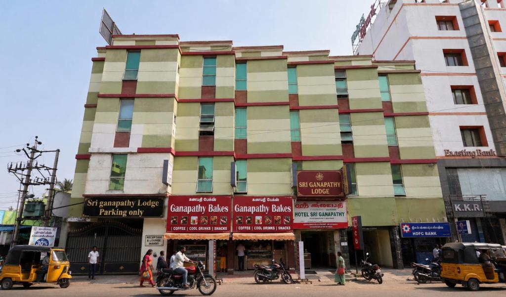 a large building on a city street with people and vehicles at Sri Ganapathy Lodge in Coimbatore