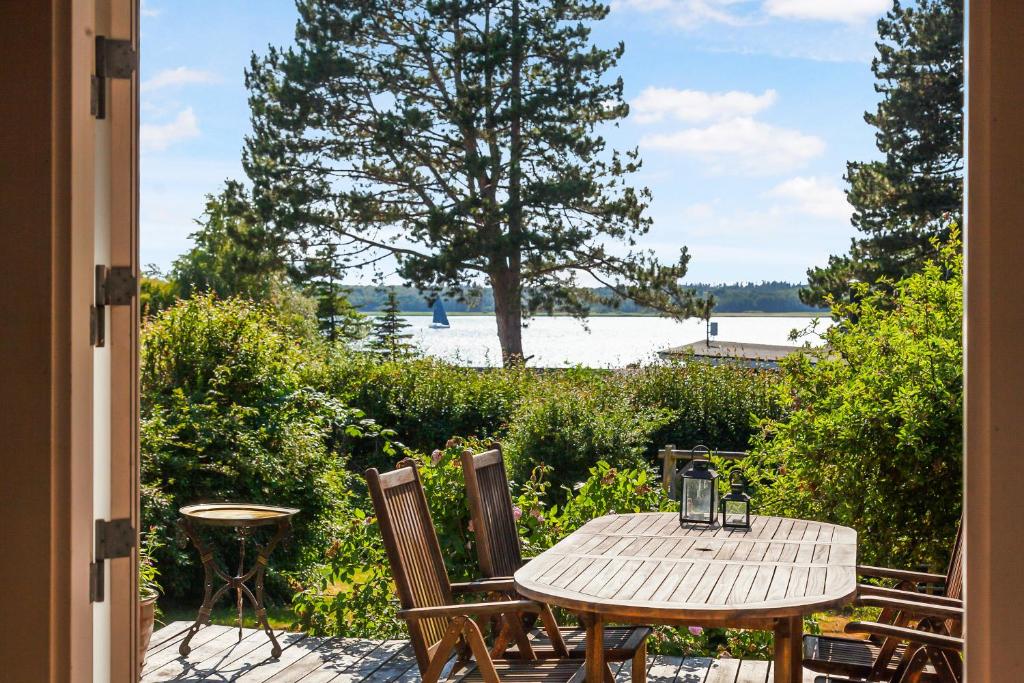 Ein Tisch und Stühle auf einer Terrasse mit Blick auf das Wasser in der Unterkunft Schönes Sommerhaus Mit Herrlichem Blick in Ølsted