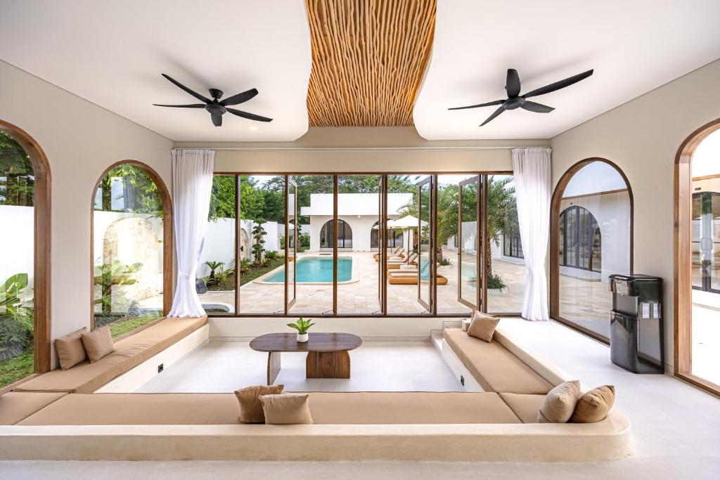 a living room with large windows and a large couch at DESAULU VILLAS - Boutique Private Room Pool View in Uluwatu