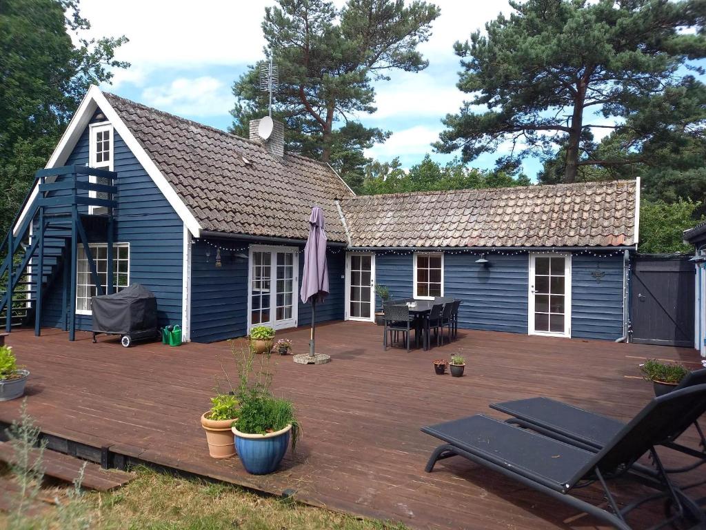 a blue house with a deck and a patio at Charming Cottage Near The Beach in Neksø