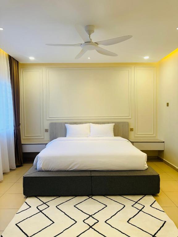 a bedroom with a white bed with a ceiling fan at Bayu senja in Lahad Datu