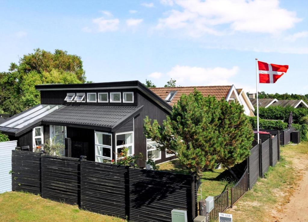 a black house with a black fence and a canadian flag at Exclusive Architect Designed Beach House in Karrebæksminde