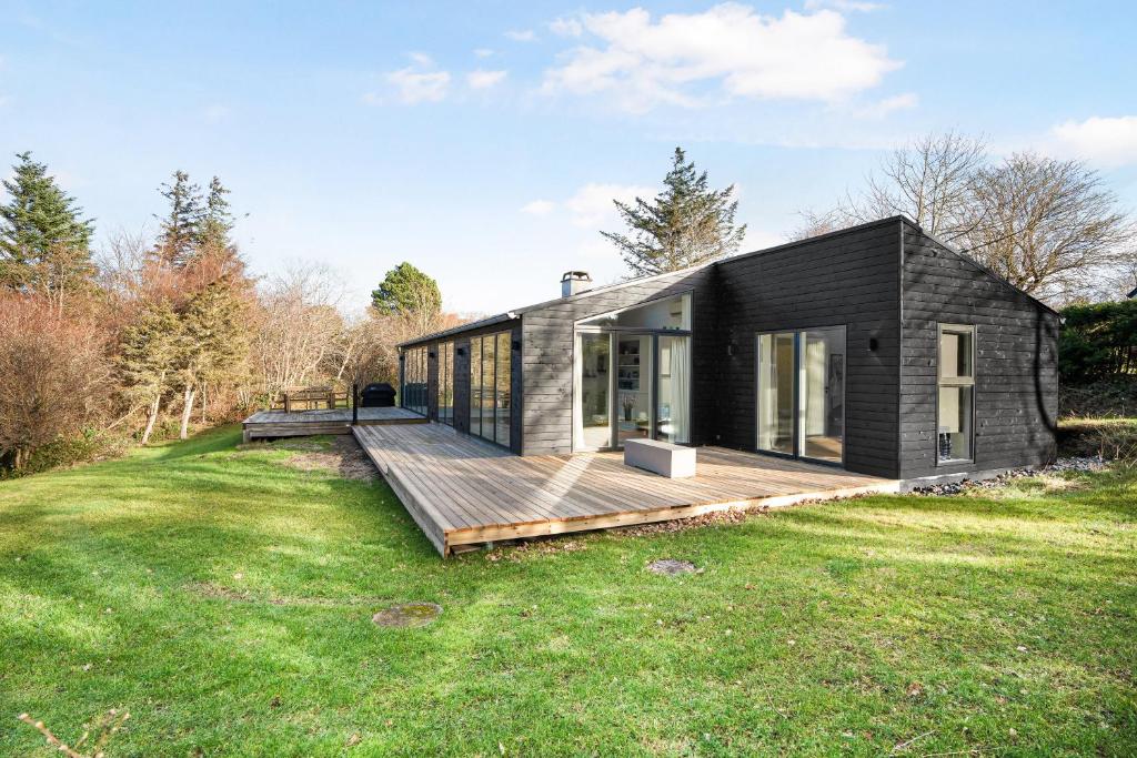 a black house with a wooden deck in a field at Unique New Beach-House I Seaview And Space in Vejby
