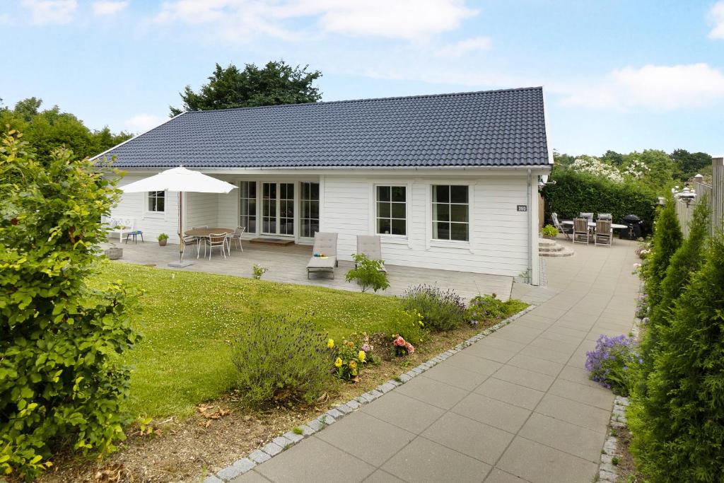 a white house with a patio and a garden at New And Cozy House By The Beach And Forest in Hornbæk