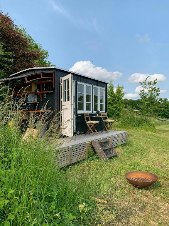 a black tiny house in a field with a table at Shepherd's Hut With Lake View In Ollerup in Vester-Skerninge