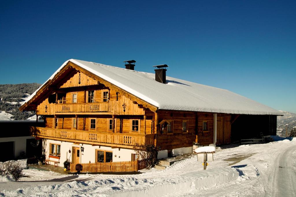 ein großes Holzhaus mit Schnee auf dem Dach in der Unterkunft Scherntreinerhof in Westendorf