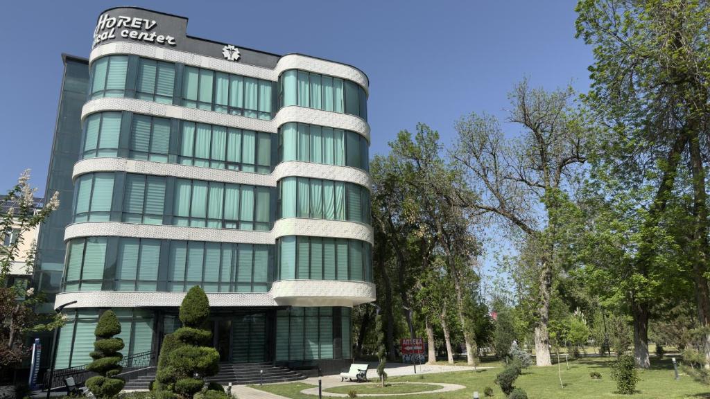 a tall green building with trees in front of it at Horev Medical Center in Tashkent