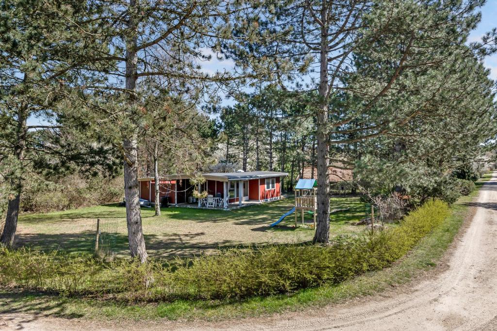 a cabin in the woods with a dirt road at Family-Friendly Cottage Close To The Water in Nykøbing Sjælland