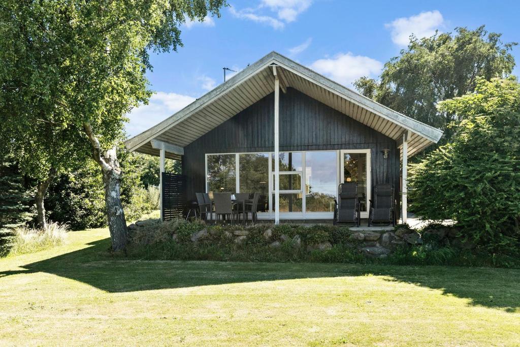 a small house with glass doors and a yard at Bright And Cozy Summer House With Sea View in Hasle