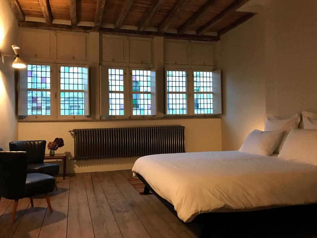 a bedroom with a large white bed and windows at Burgstraat 8 in Ghent