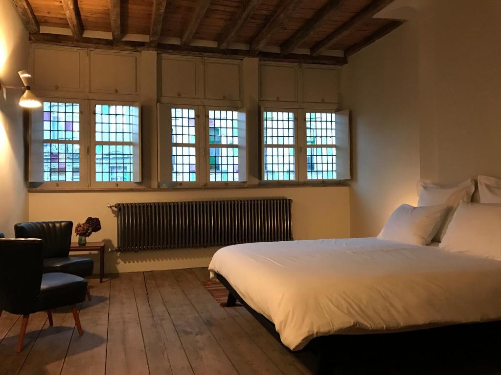 - une chambre avec un grand lit blanc et des fenêtres dans l'établissement Burgstraat 8, à Gand