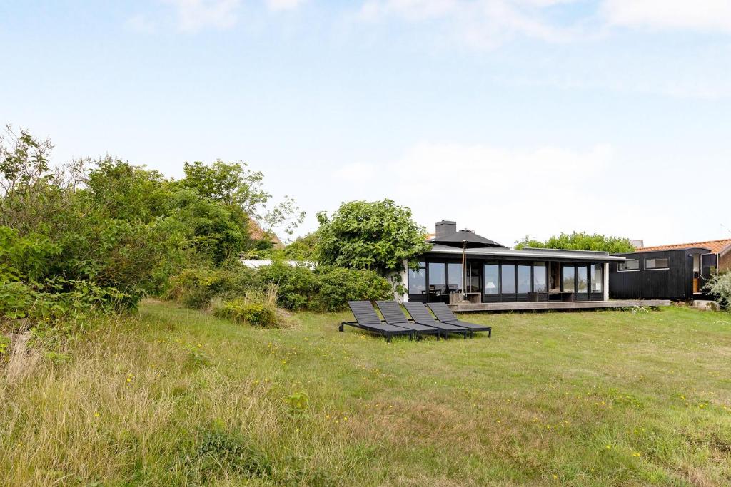 a group of benches sitting in the grass in front of a house at Architect Designed Holiday Home With Sea View in Gudhjem