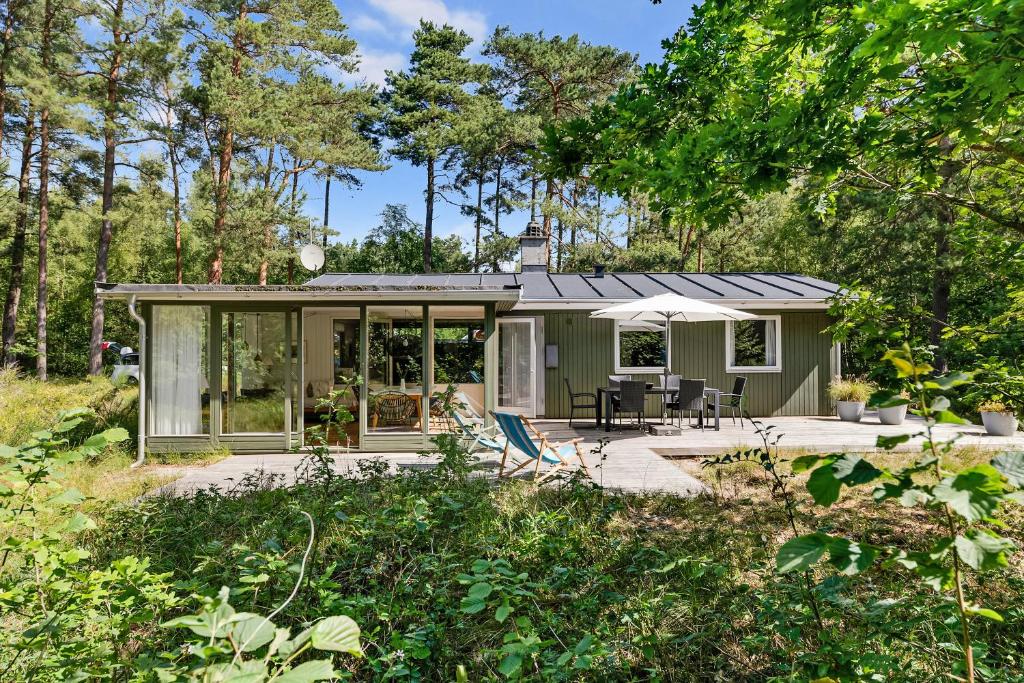 a green tiny house with a patio in the woods at Cottage In Peaceful Surroundings In Vester Sømark in Vester Sømarken