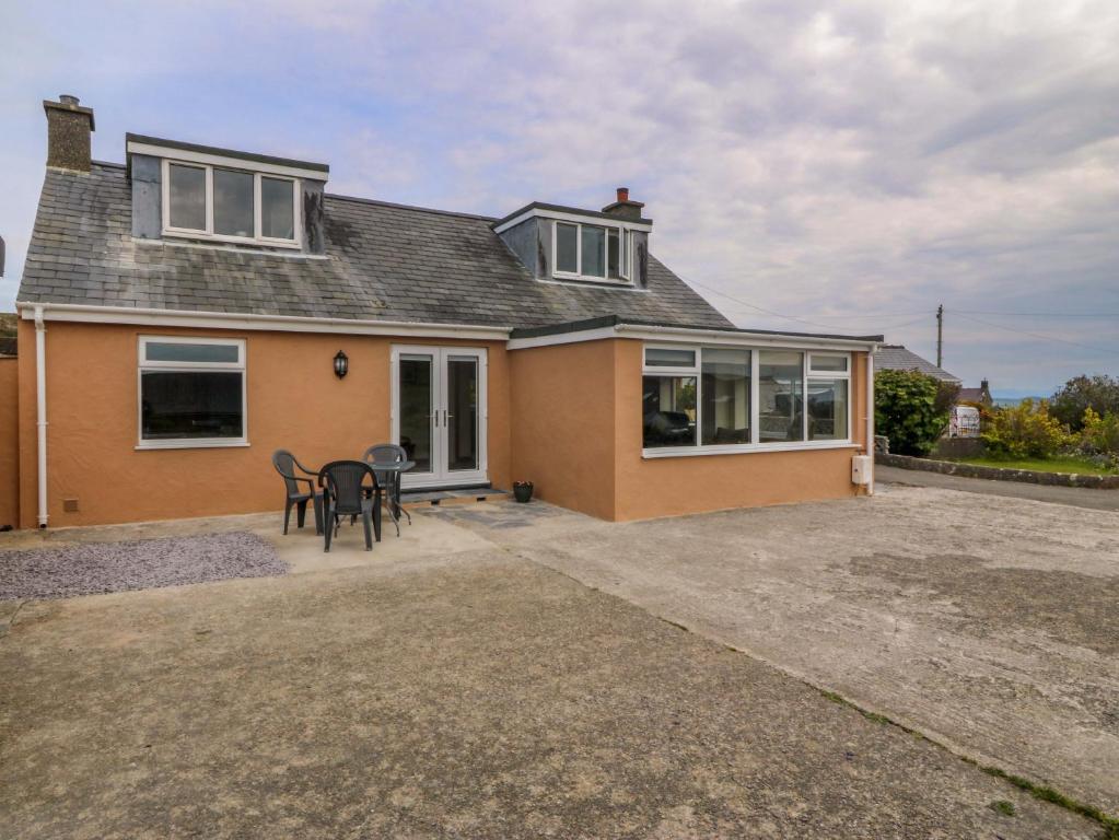 a house with a table and chairs in front of it at Dalar Deg in Rhiw