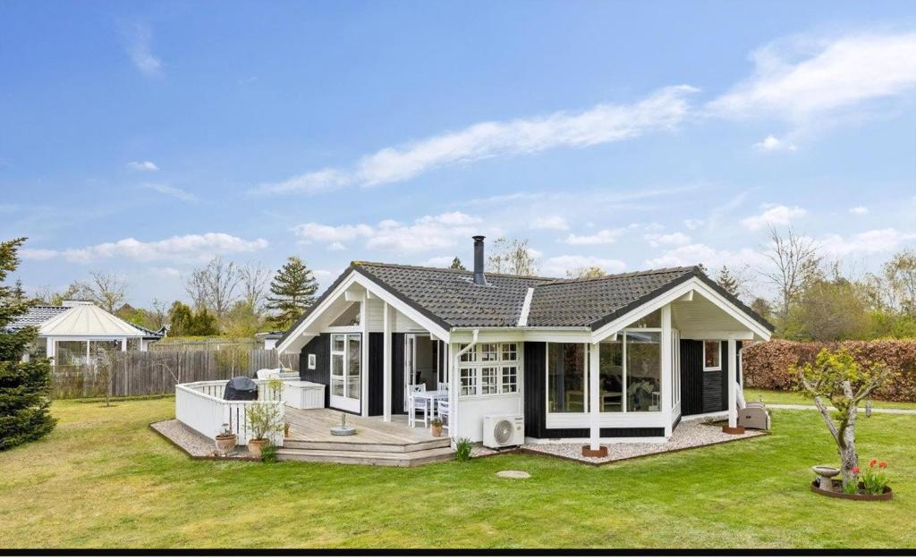 a small white house with a deck in a yard at Cozy And Well-Maintained Holiday Home in Eskebjerg
