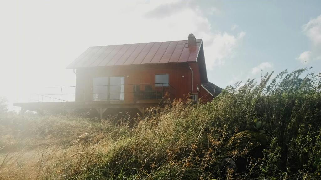 a house on top of a hill with tall grass at Rural Cottage With Views Over Herrljunga in Ljung
