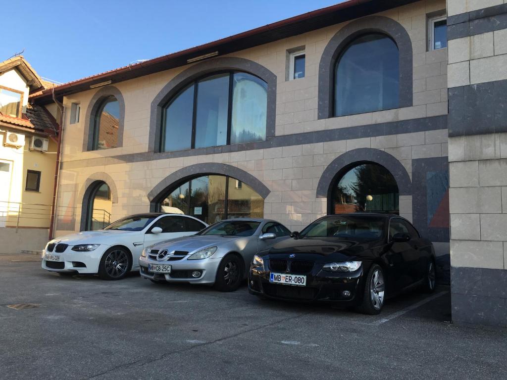 drie auto's geparkeerd op een parkeerplaats voor een gebouw bij Rooms & Apartments Banjac in Maribor